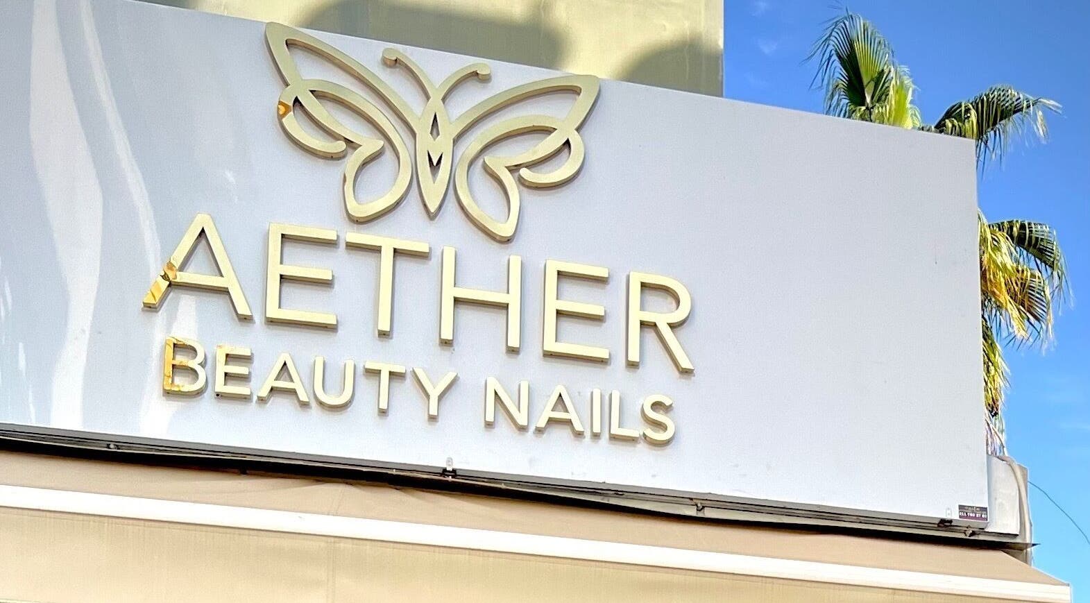 Aether Beauty Nails storefront sign with butterfly logo in Glifada, GR.