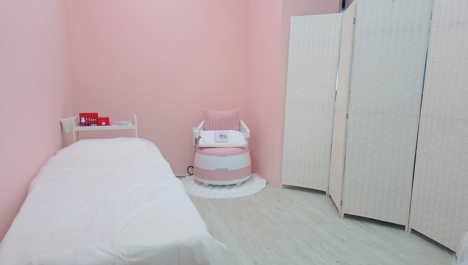 Blossom Glow's serene pink treatment room in Singapore, SG, showcasing a relaxing chair and cozy bed.