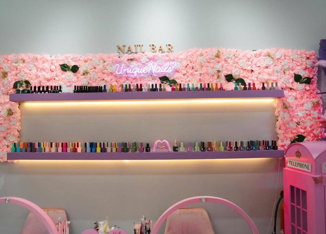 Chic nail bar with pink floral decor at Unique Station Beauty Salon, Dubai, AE. Vibrant nail polish display.