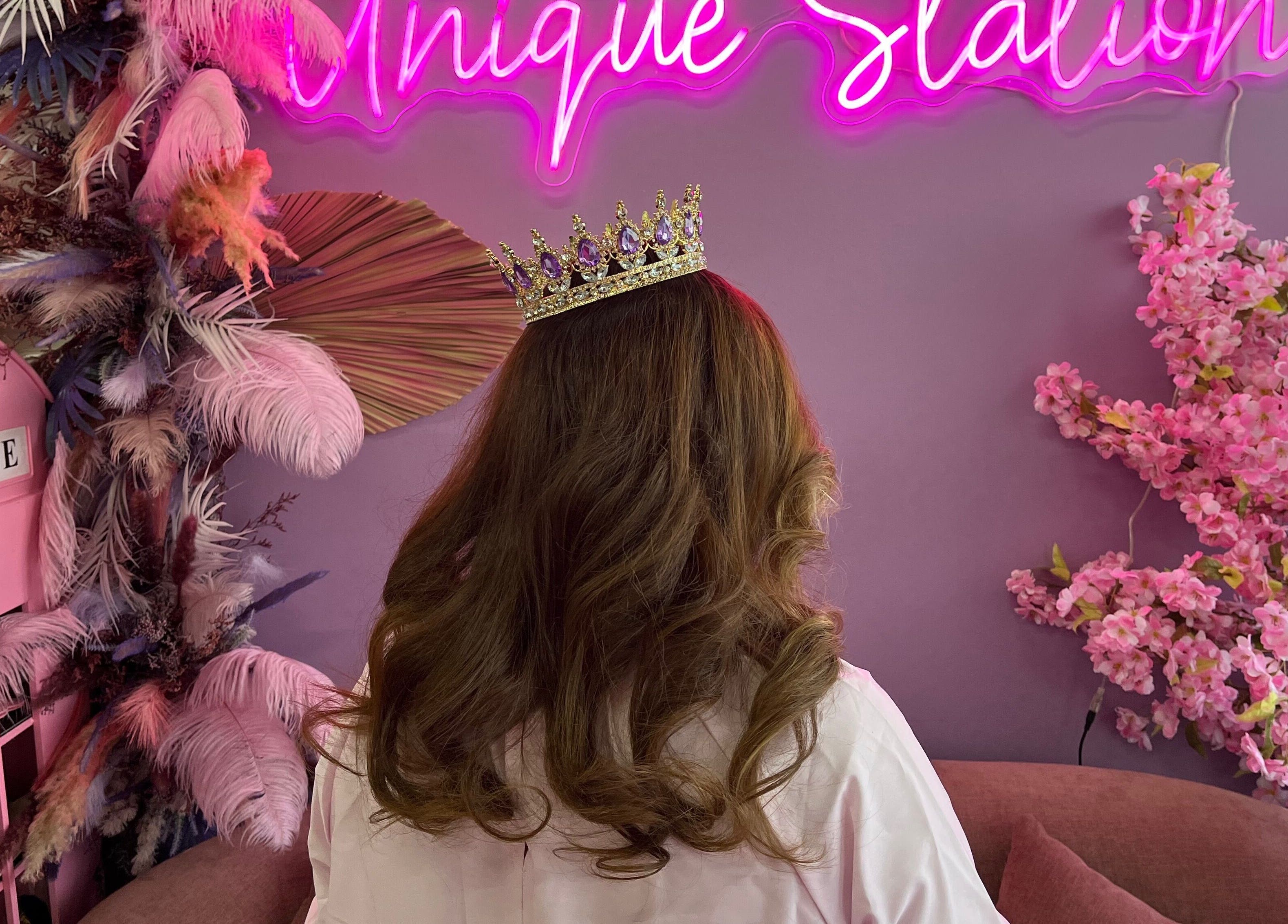 Crowned woman at Unique Station Beauty Salon with pink floral decor, Dubai, AE.