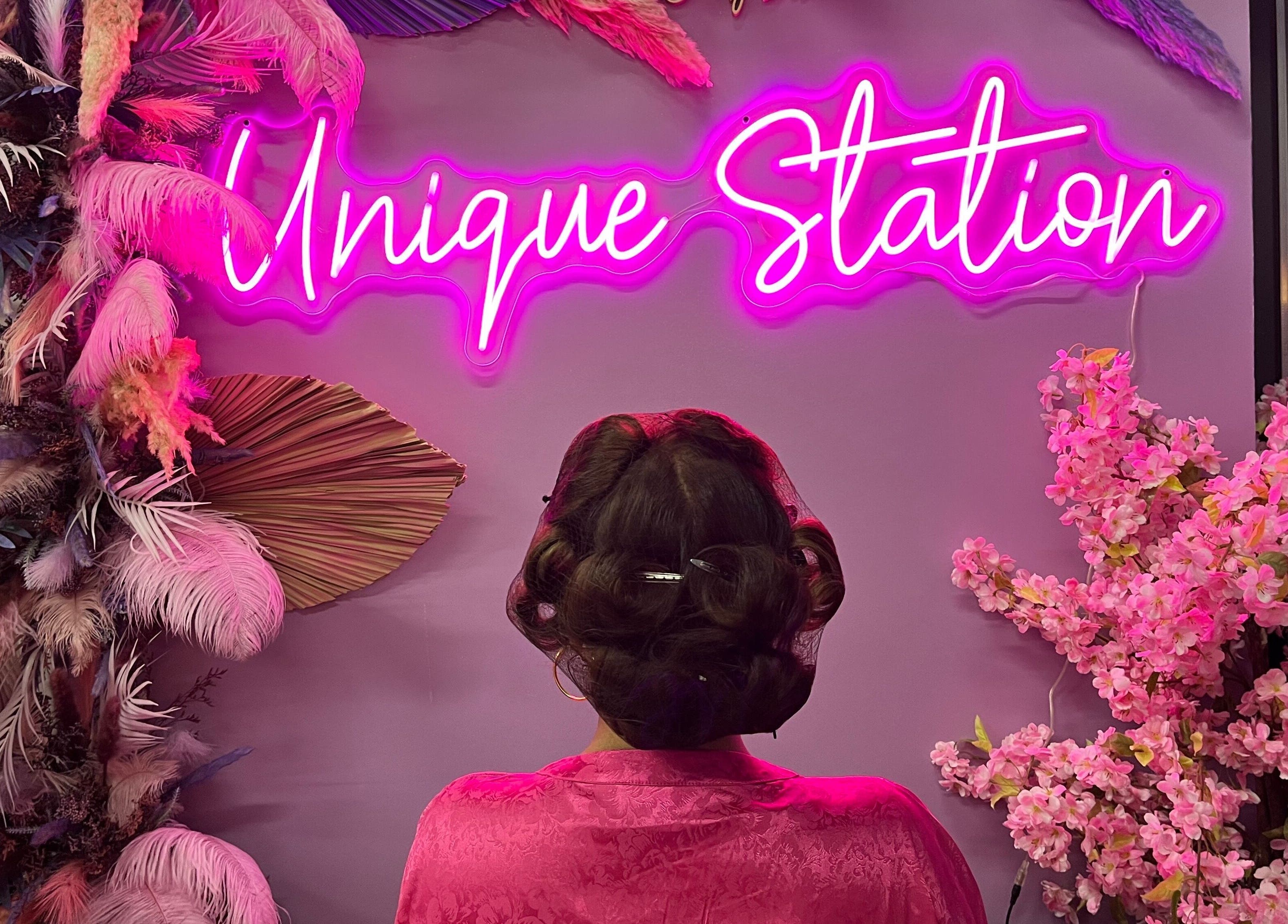 Unique Station Beauty Salon in Dubai, AE features vibrant neon pink decor with floral accents.