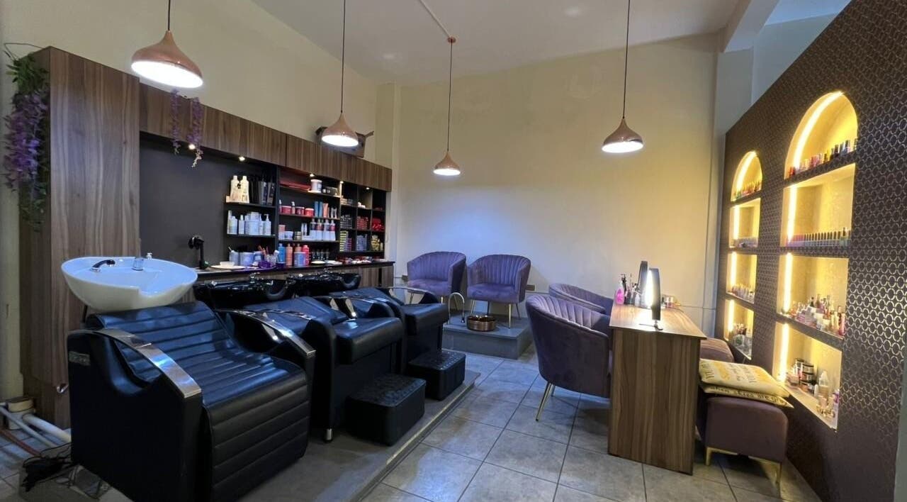 Intérieur moderne de Clau Beauty Studio à Cochabamba, incluant sièges confortables et étagères éclairées.