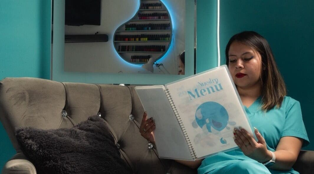 Profesional leyendo menú en Gotita Studio, Ciudad De México, MX, junto a un sillón cómodo.