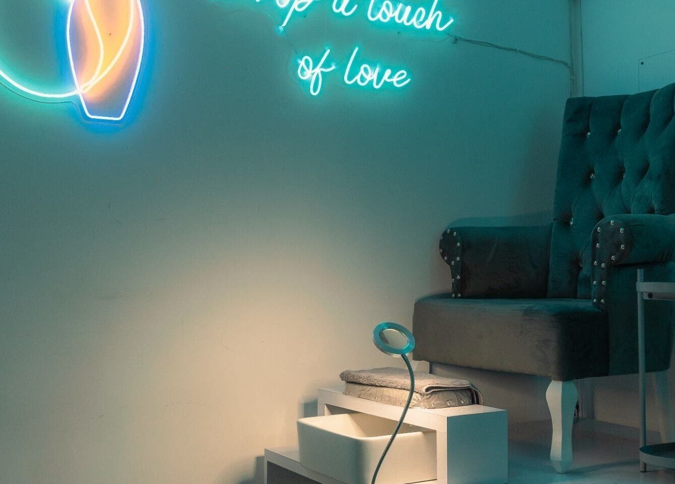 Espacio acogedor en Gotita Studio, Ciudad De México, con silla de terciopelo y luces de neón.