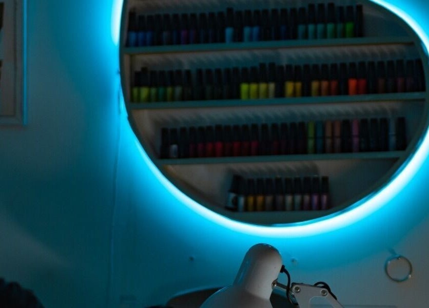 Estante de esmaltes en Gotita Nails, Ciudad De México, MX con espejo iluminado azul.