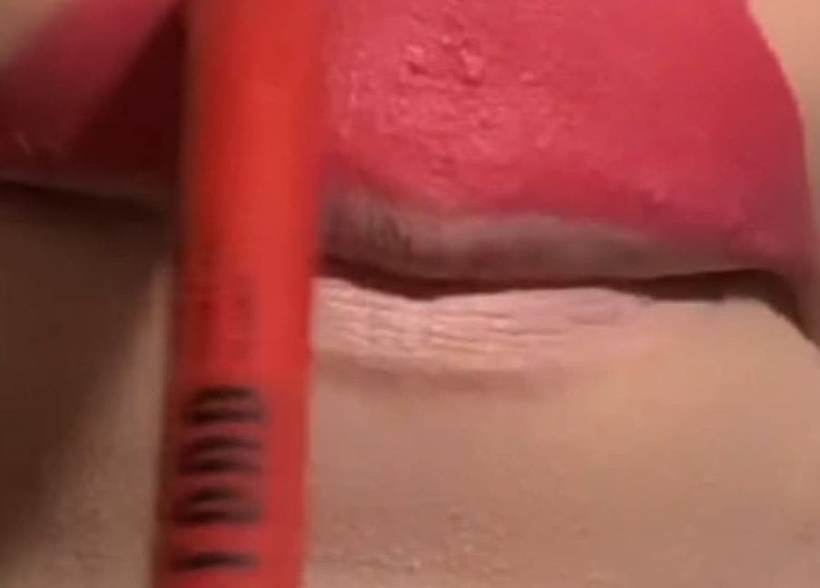 Applying pink lip color at Glowbit, Abuja, Federal Capital Territory, NG for a fresh look.