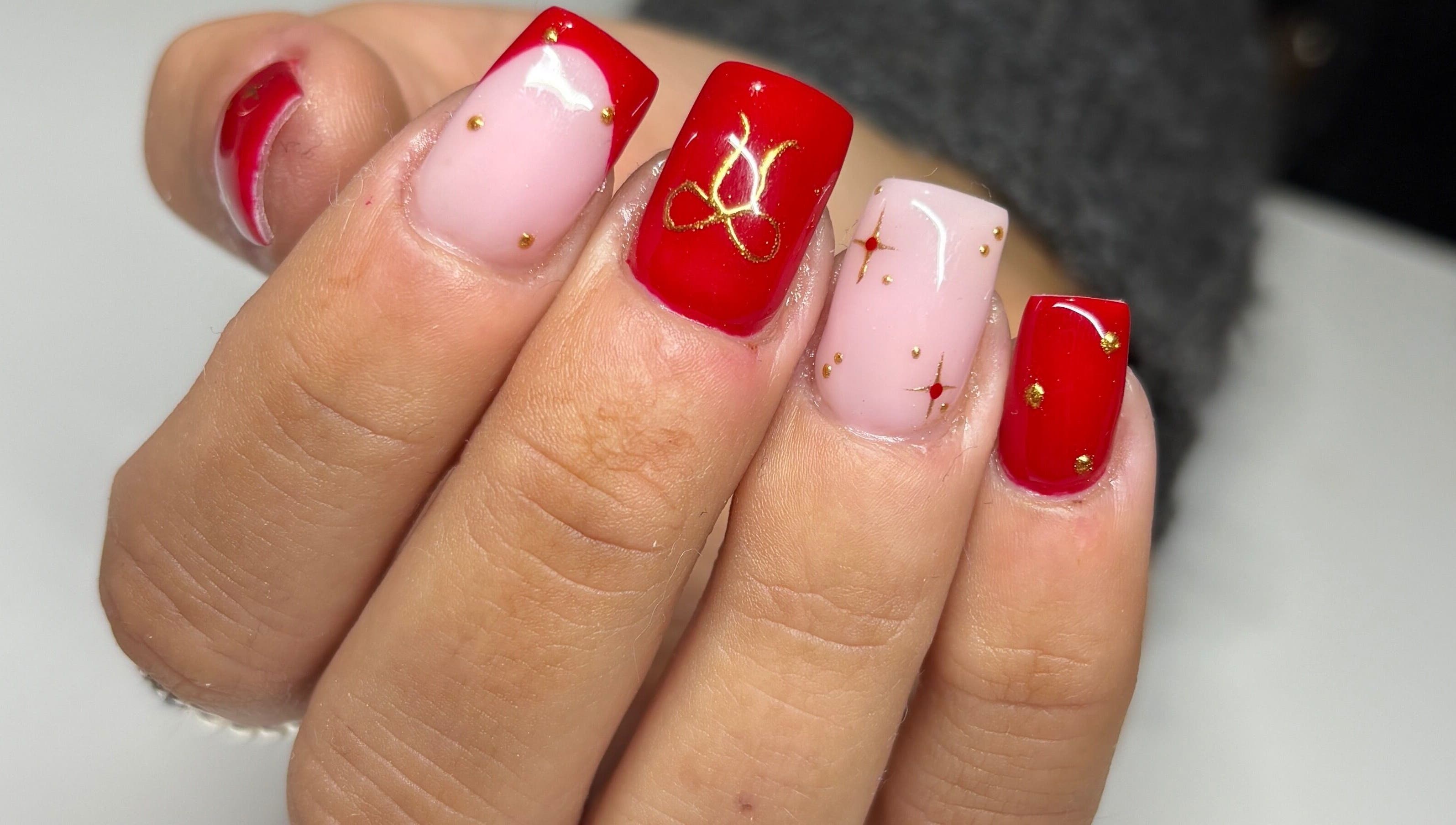 Stunning red and pink nail art with gold accents at Paint Them Nails With Amina, Stoke-on-Trent, England, GB.