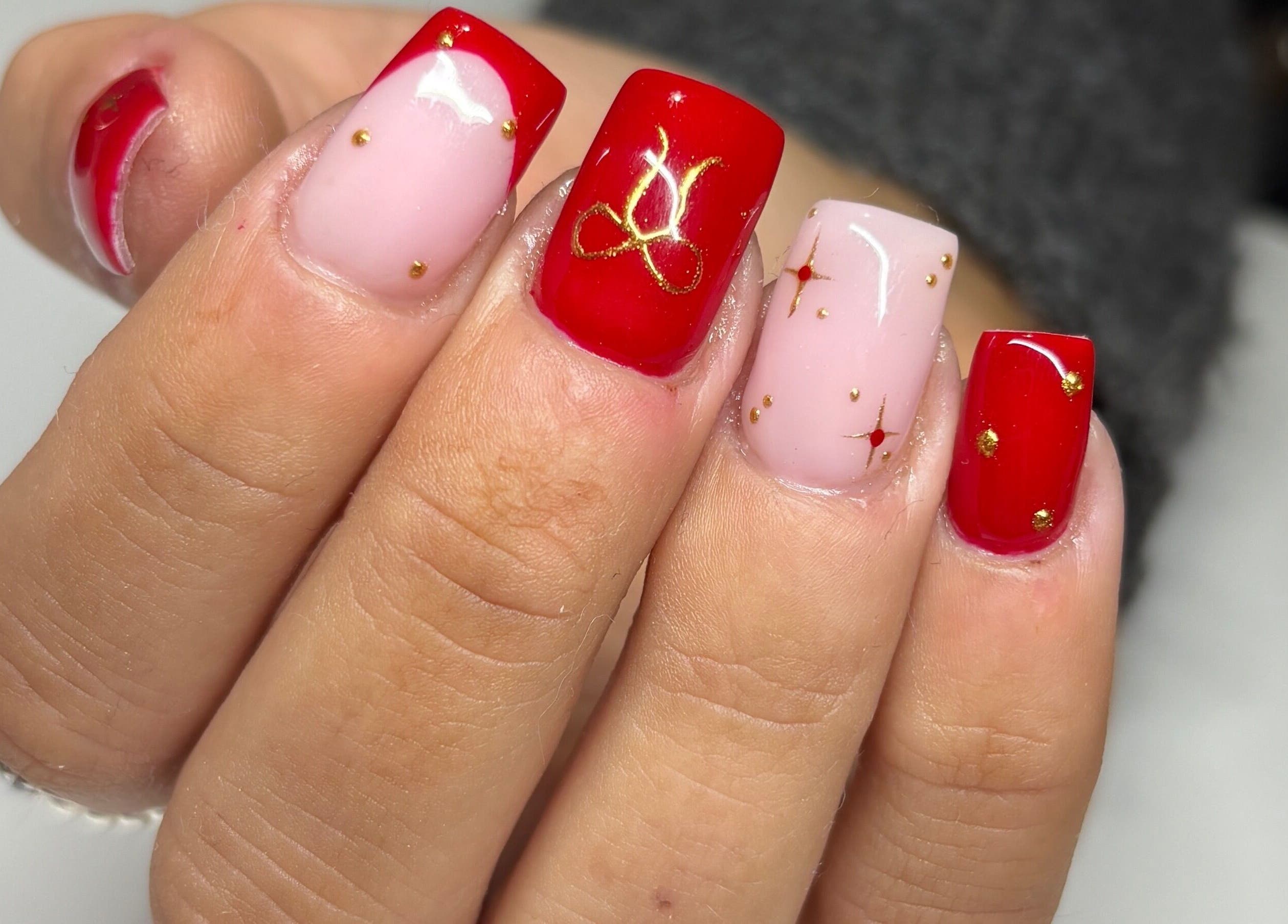 Stunning red and pink nail art with gold accents at Paint Them Nails With Amina, Stoke-on-Trent, England, GB.