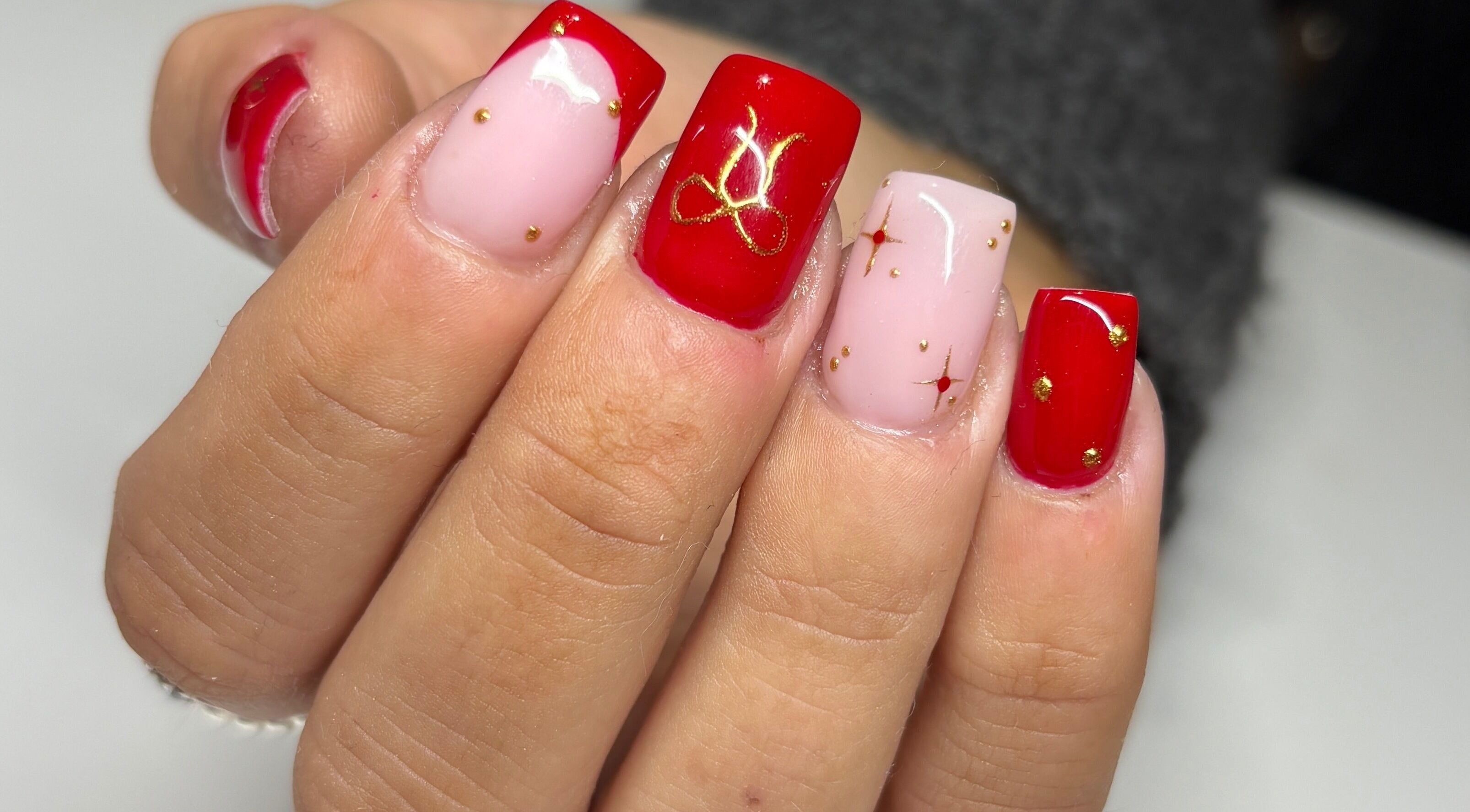Stunning red and pink nail art with gold accents at Paint Them Nails With Amina, Stoke-on-Trent, England, GB.