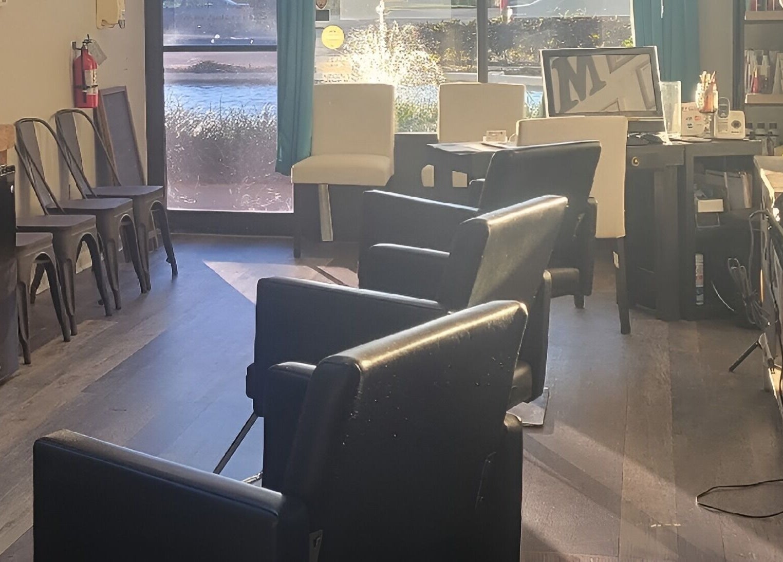 Sunlit seating area inside Meraki Salon, Port St. Lucie, Florida, US, with modern decor and comfy chairs.