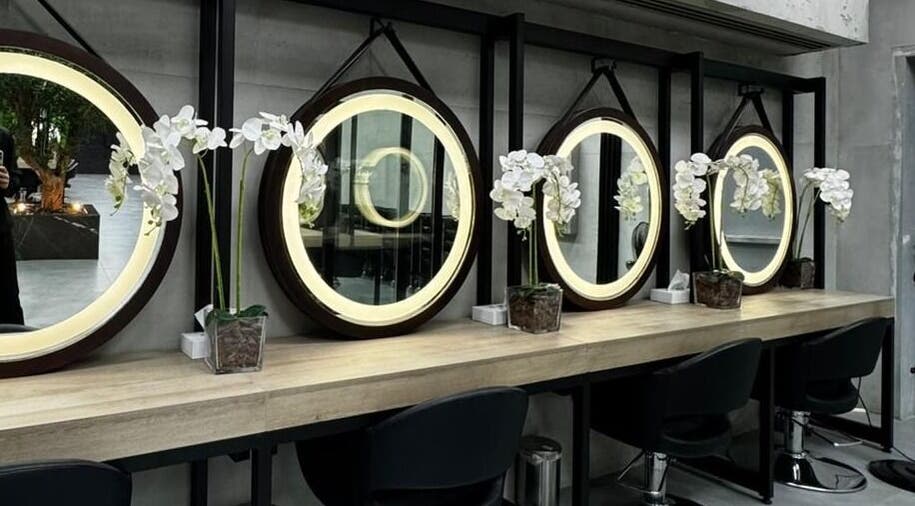 تصميم داخلي عصري في Brazil Studio Salon - Riyadh، الرياض، مقاطعة الرياض، SA يعرض مرايا دائرية وأزهار بيضاء.