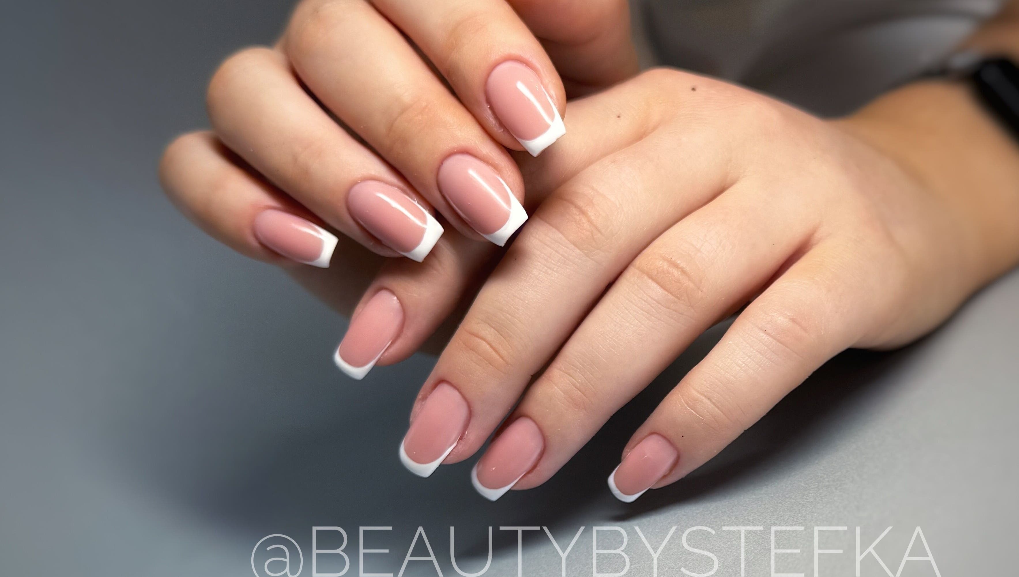 Elegant French manicure at SKA.NAILS in Norwich, England, GB, showcasing glossy nude and white nail art.