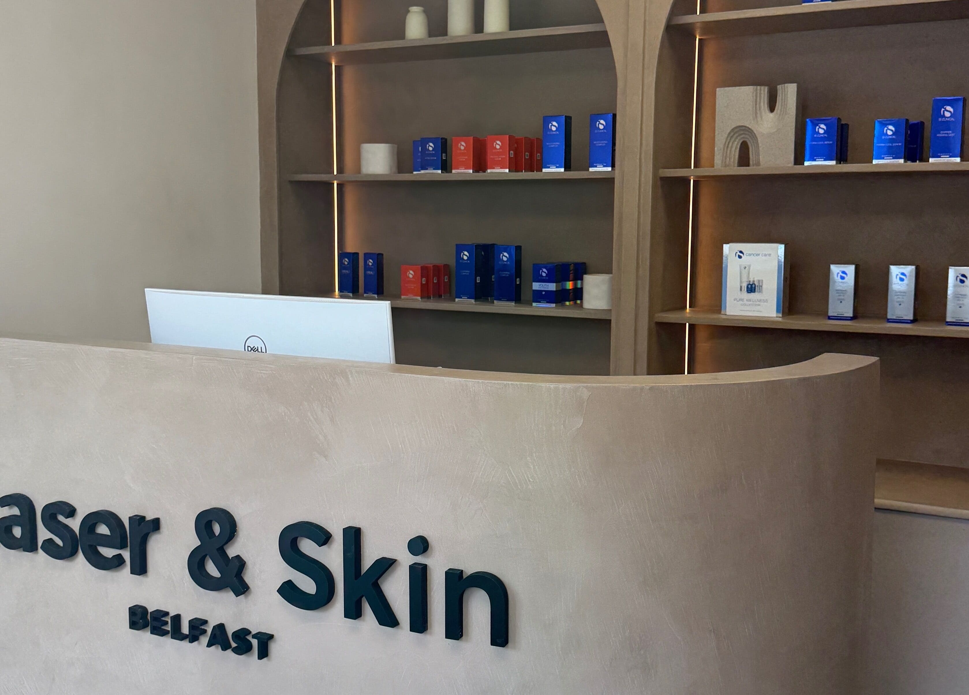 Reception at Laser & Skin Belfast in Belfast, Northern Ireland, GB showcasing beauty products on wooden shelves.