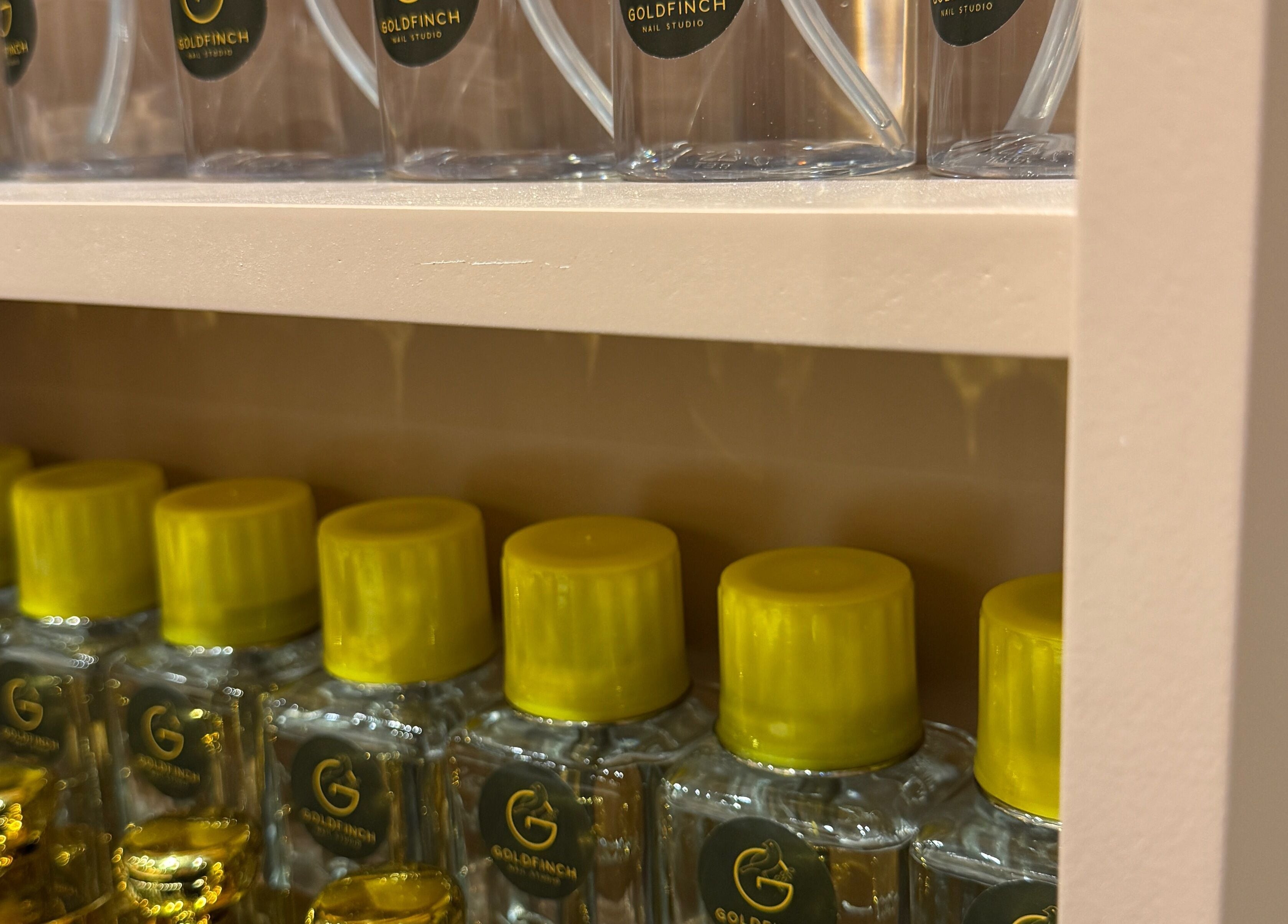 Shelf of Goldfinch Nails Studio products in Haslemere, England, GB with yellow-capped bottles.