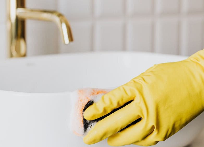 A gloved hand cleans a pristine sink at Warch Airbnb Care, Coolangatta, Queensland, AU.