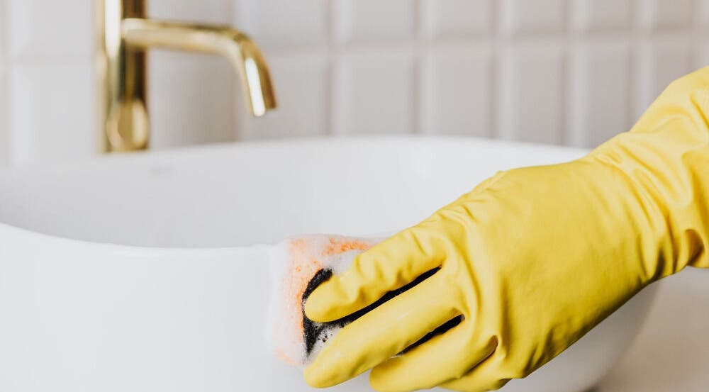 A gloved hand cleans a pristine sink at Warch Airbnb Care, Coolangatta, Queensland, AU.