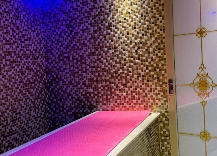 Luxurious spa room at Bronzette Beauty Salon L.L.C, Dubai, AE, with elegant mosaic walls and a pink massage table.