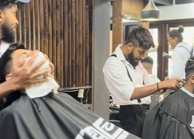 Barbers at Raula Barbershop Park Road in Colombo performing a haircut and hot towel treatment.