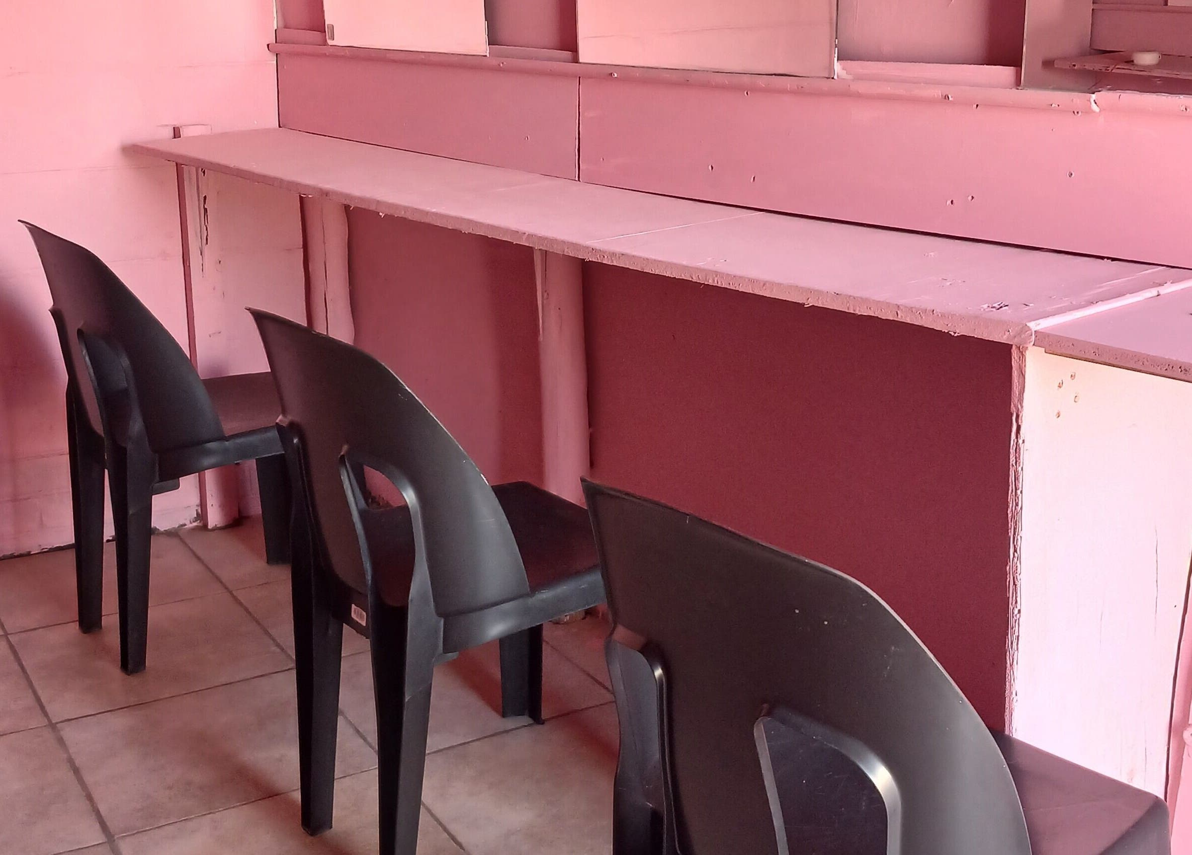 Pink interior seating area at Majona Hairsalon, Swakopmund, Erongo Region, NA with black chairs.