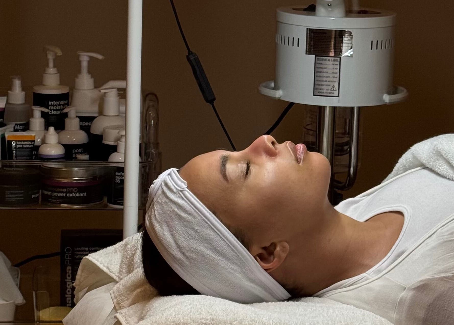 Client enjoys facial treatment at Plump Facial Bar, Riyadh, Riyadh Province, SA, surrounded by skincare products.