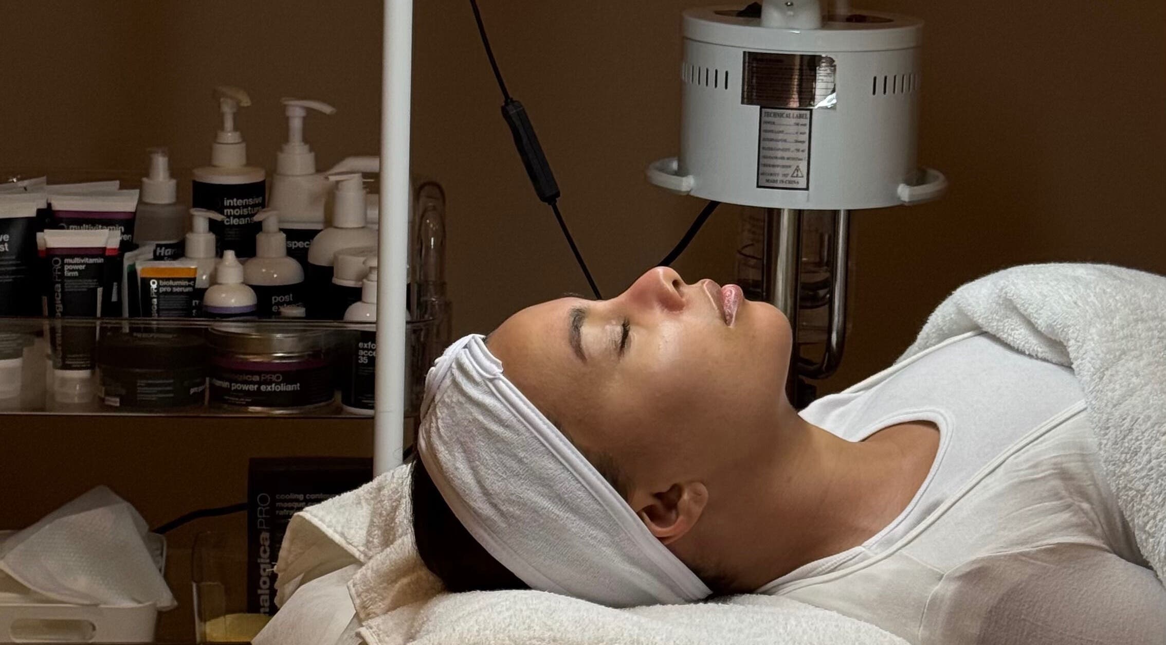 Client enjoys facial treatment at Plump Facial Bar, Riyadh, Riyadh Province, SA, surrounded by skincare products.