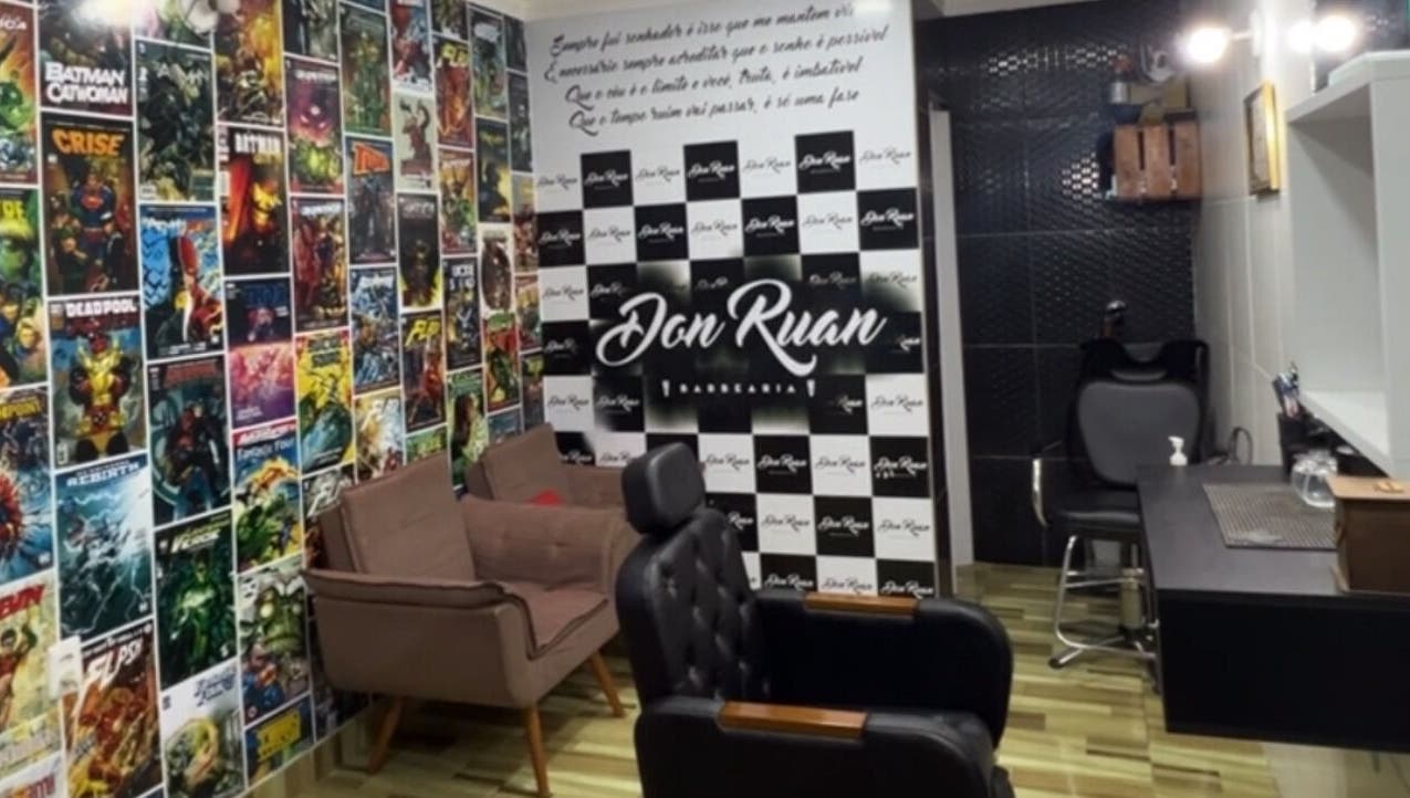 Interior colorido da Barbearia Don Ruan em Bahia, Bahia, BR, com parede de quadrinhos e cadeiras confortáveis.