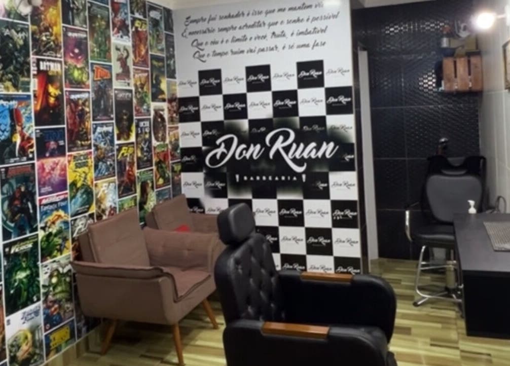 Interior colorido da Barbearia Don Ruan em Bahia, Bahia, BR, com parede de quadrinhos e cadeiras confortáveis.