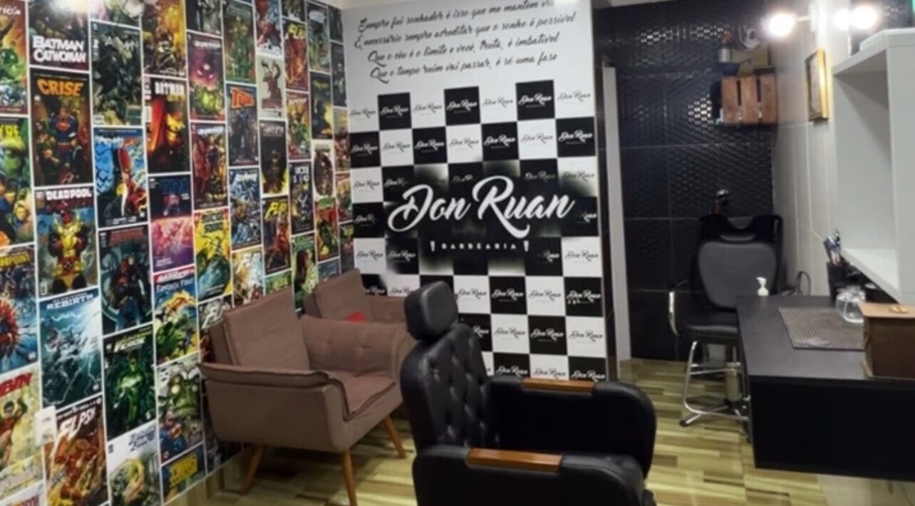 Interior colorido da Barbearia Don Ruan em Bahia, Bahia, BR, com parede de quadrinhos e cadeiras confortáveis.
