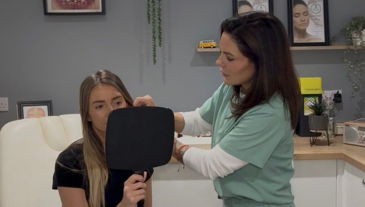 Expert consultation at JDL Aesthetics in Whitley Bay, England, GB with a patient holding a mirror.
