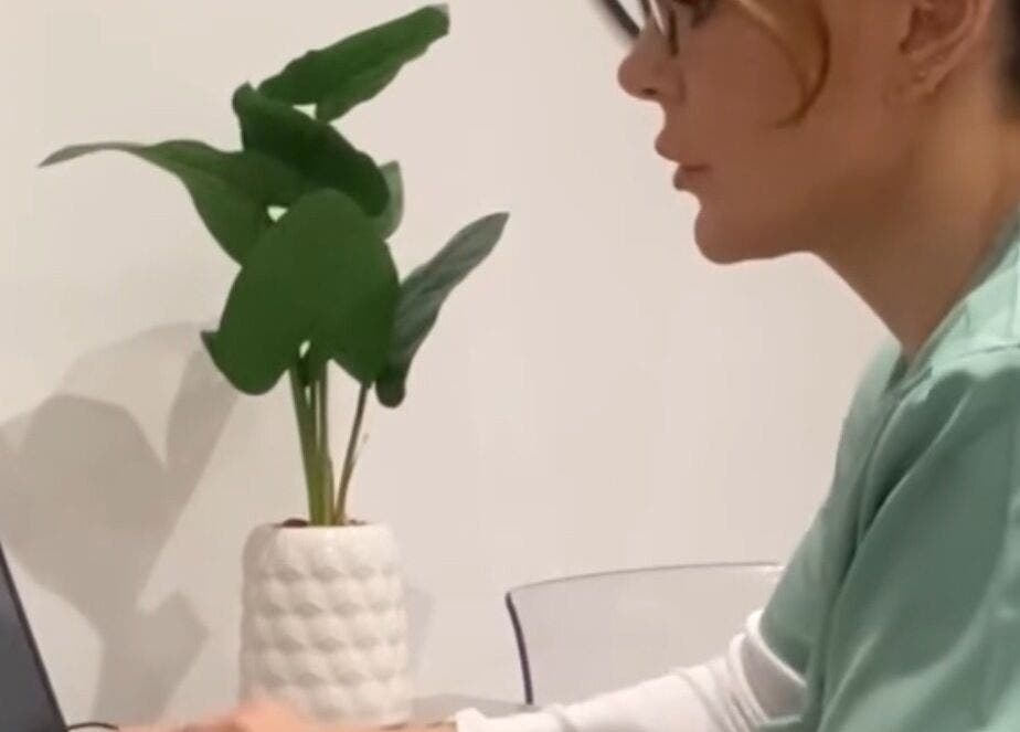 A professional at JDL Aesthetics in Whitley Bay, England, GB, working at a laptop beside a plant.