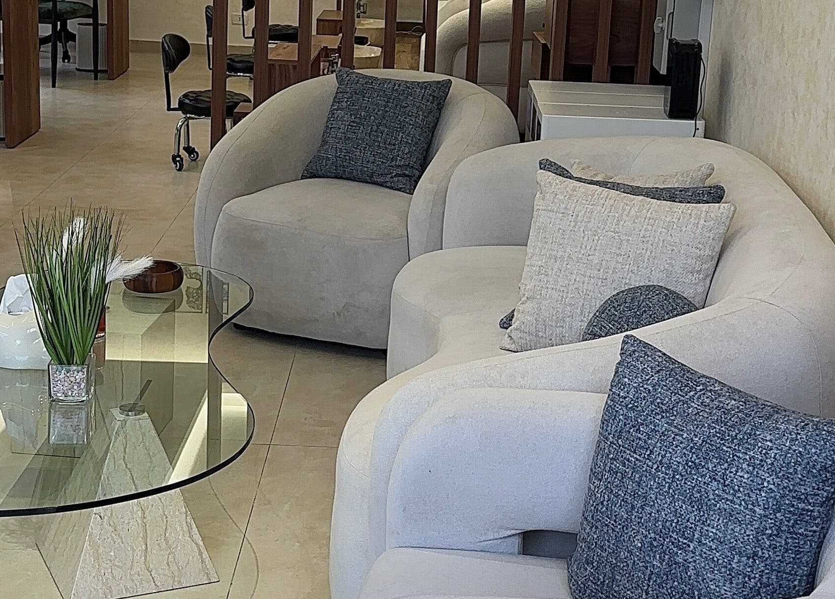 Cozy seating area in Joelle Beauty Lounge, Bayrut, LB, featuring plush sofas and a stylish glass table.