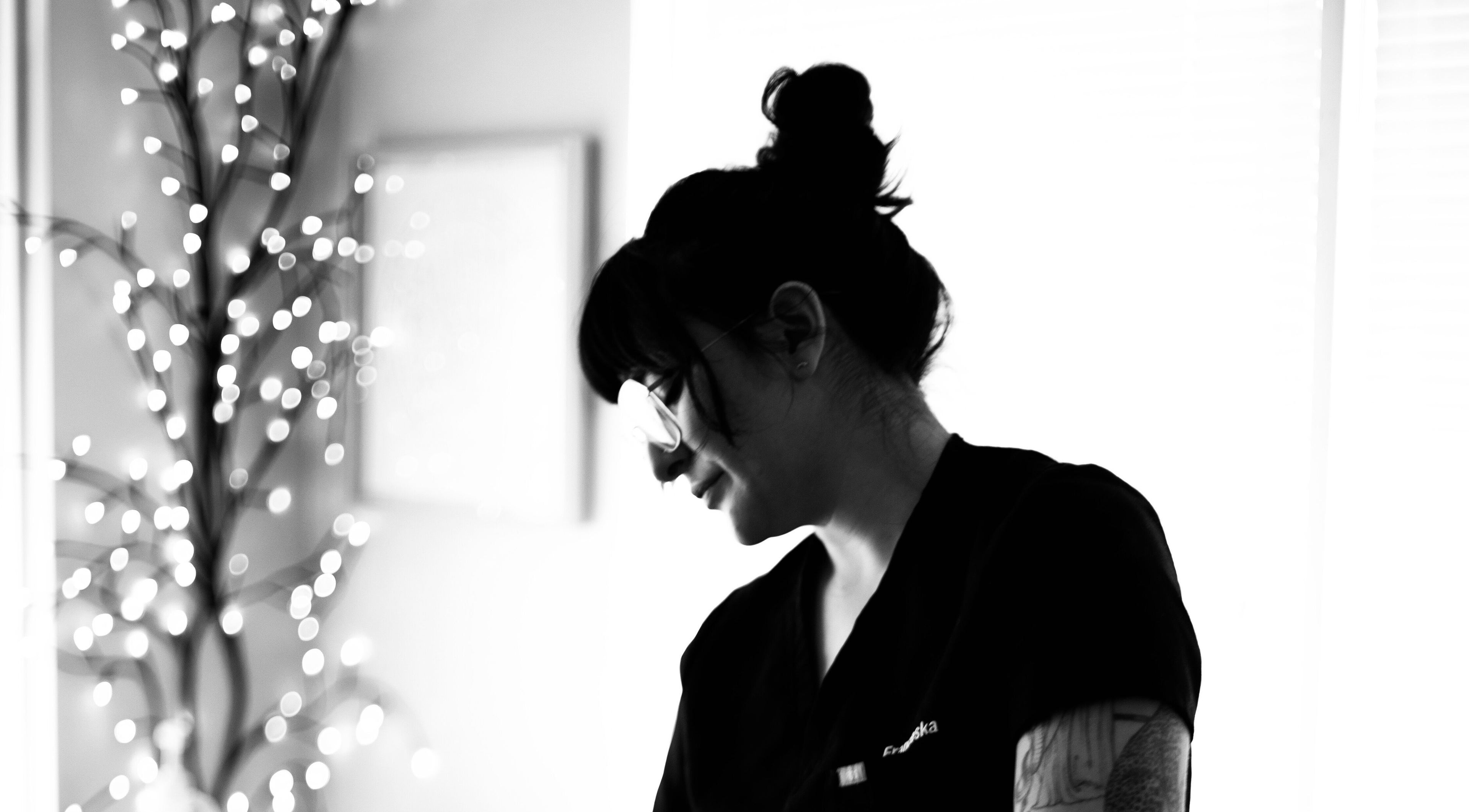 Wellness specialist at Yellow Butterfly Wellness, Albuquerque, New Mexico, US, smiling by decorative lights.