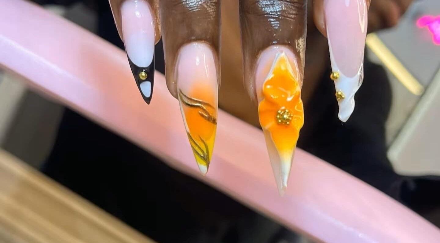 Bold, floral nail art at The Beys Signature, Lagos, Lagos, NG. Vibrant orange designs with gold accents.