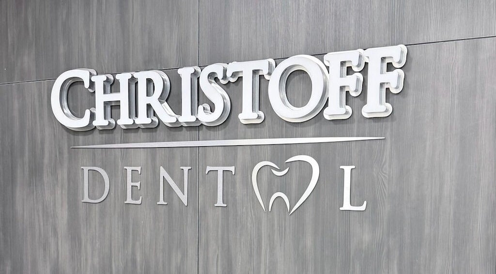 Лого на Christoff Dental в София, Софийска област, BG на сива дървена стена.