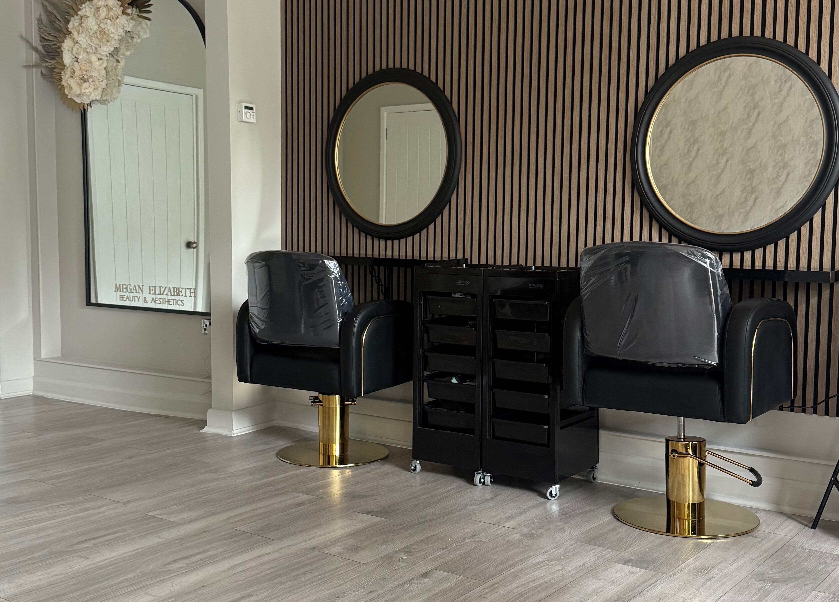 Elegant styling chairs at Megan Elizabeth Beauty & Aesthetics, Birmingham, England, GB with mirrors on a striped wall.
