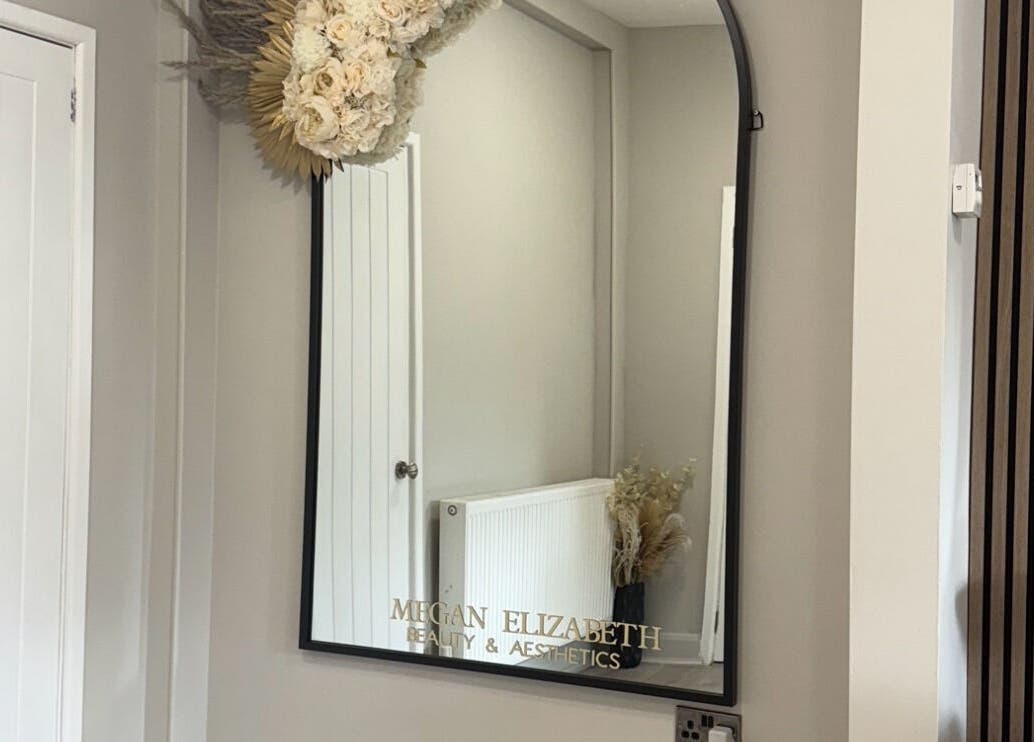 Elegant mirror at Megan Elizabeth Beauty & Aesthetics, Birmingham, England, GB with floral decor above.
