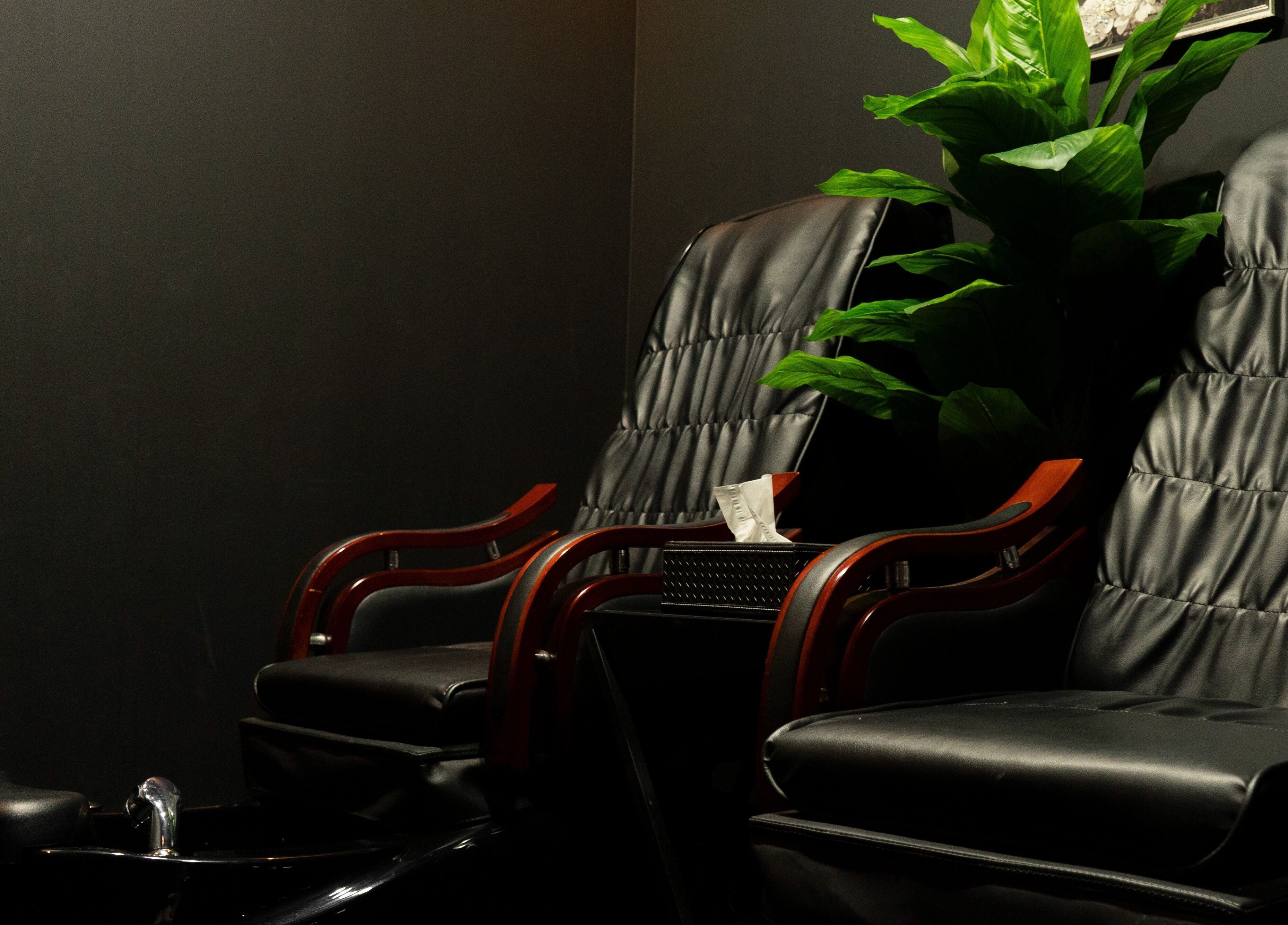 Comfortable seating area at Excluser Gents Salon L.L.C, Dubai, AE, featuring plush black chairs and greenery.