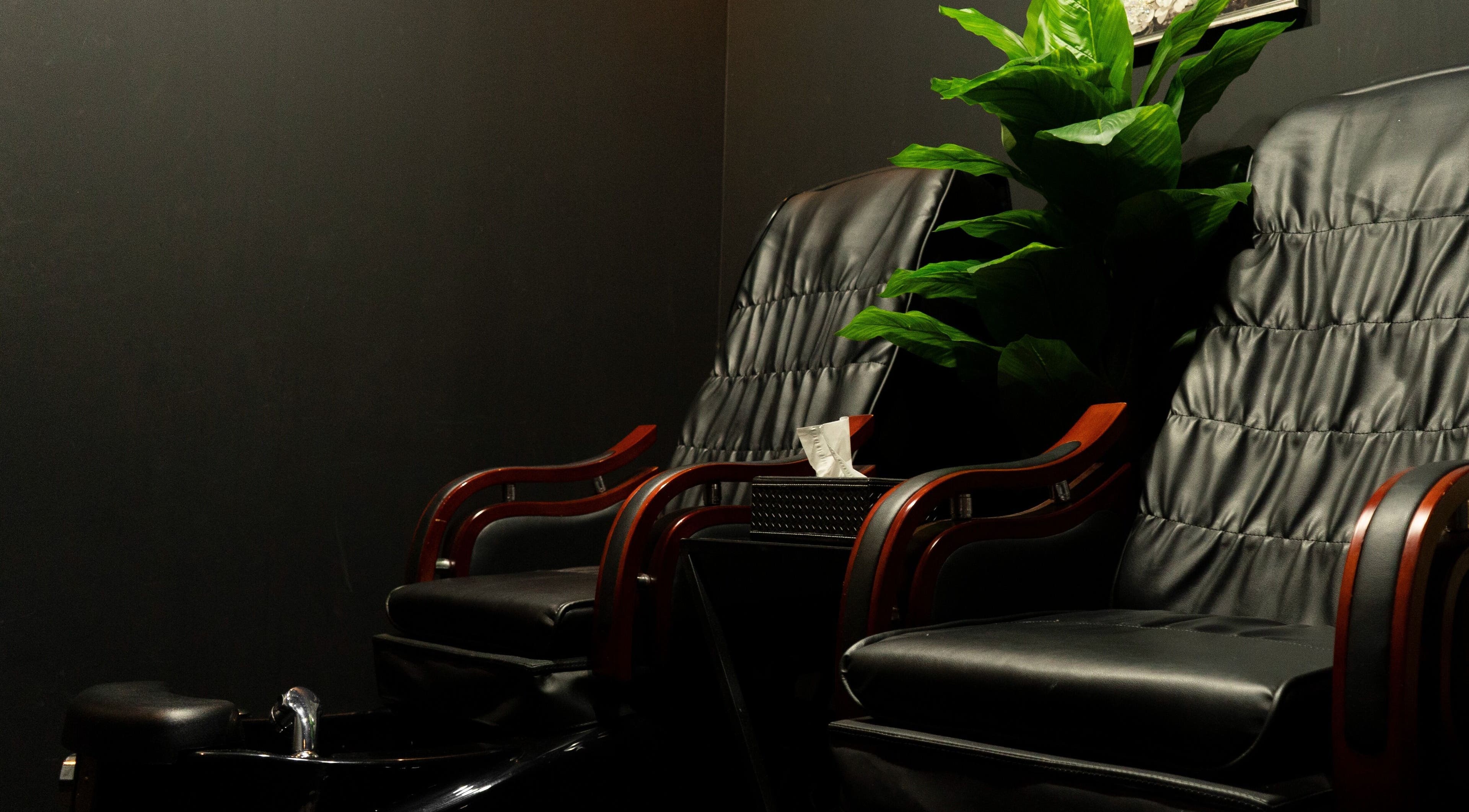 Comfortable seating area at Excluser Gents Salon L.L.C, Dubai, AE, featuring plush black chairs and greenery.