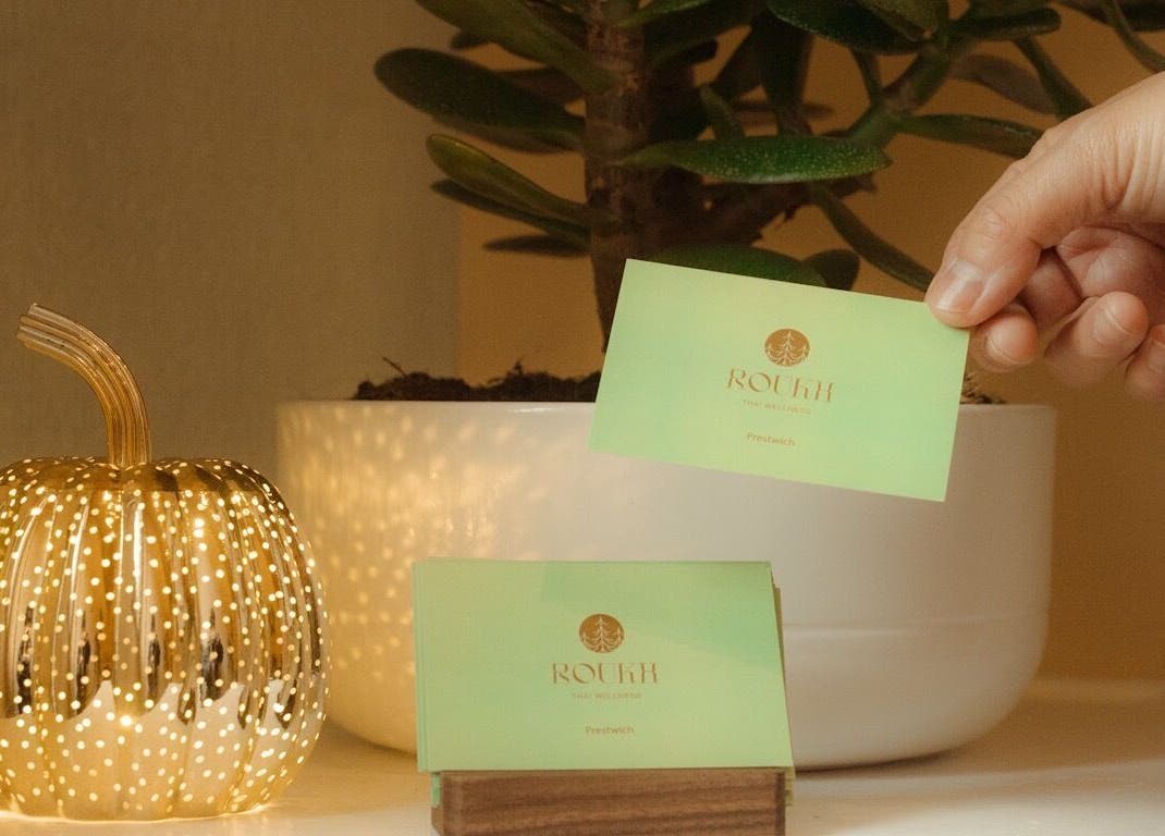 Hand with a Roukh Thai Wellness Prestwich card in cozy setting, Manchester, England, GB.