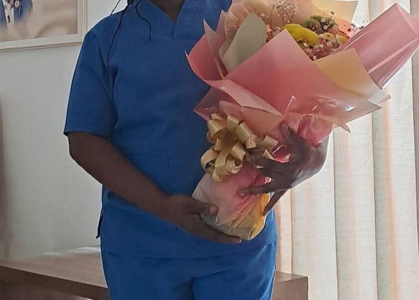 Staff holding bouquet at Mariam Massage, muscat, OM, symbolizing warmth and care in wellness service.
