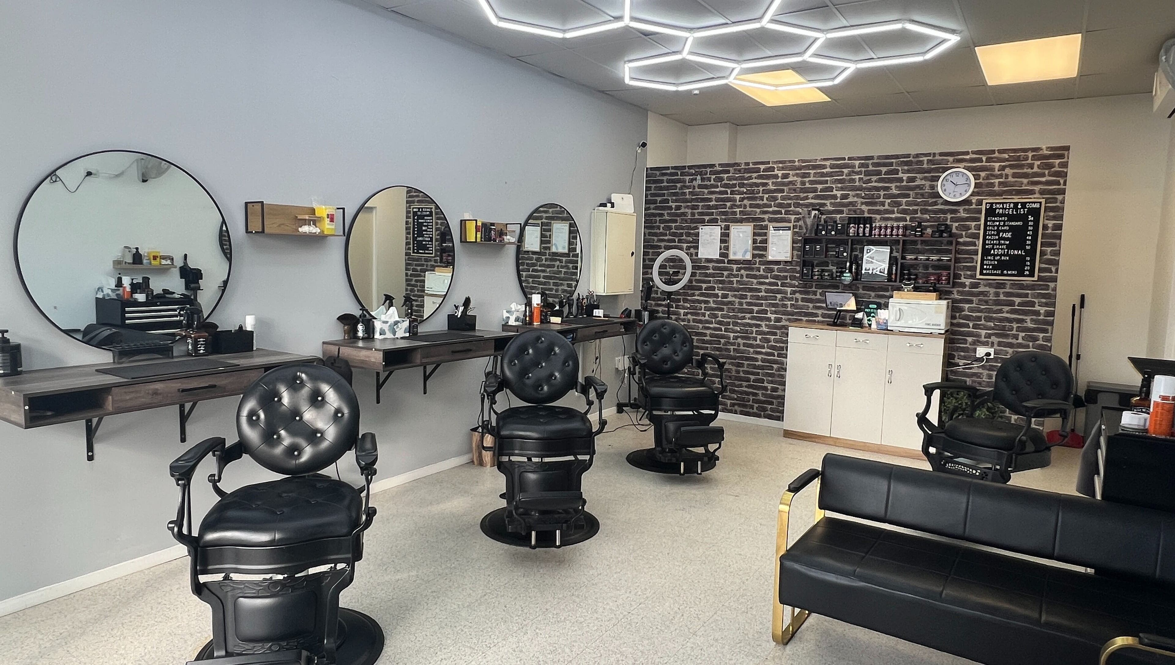 Modern interior of D' Shaver And Comb Barbershop, Auckland, NZ, featuring sleek black chairs and mirrors.