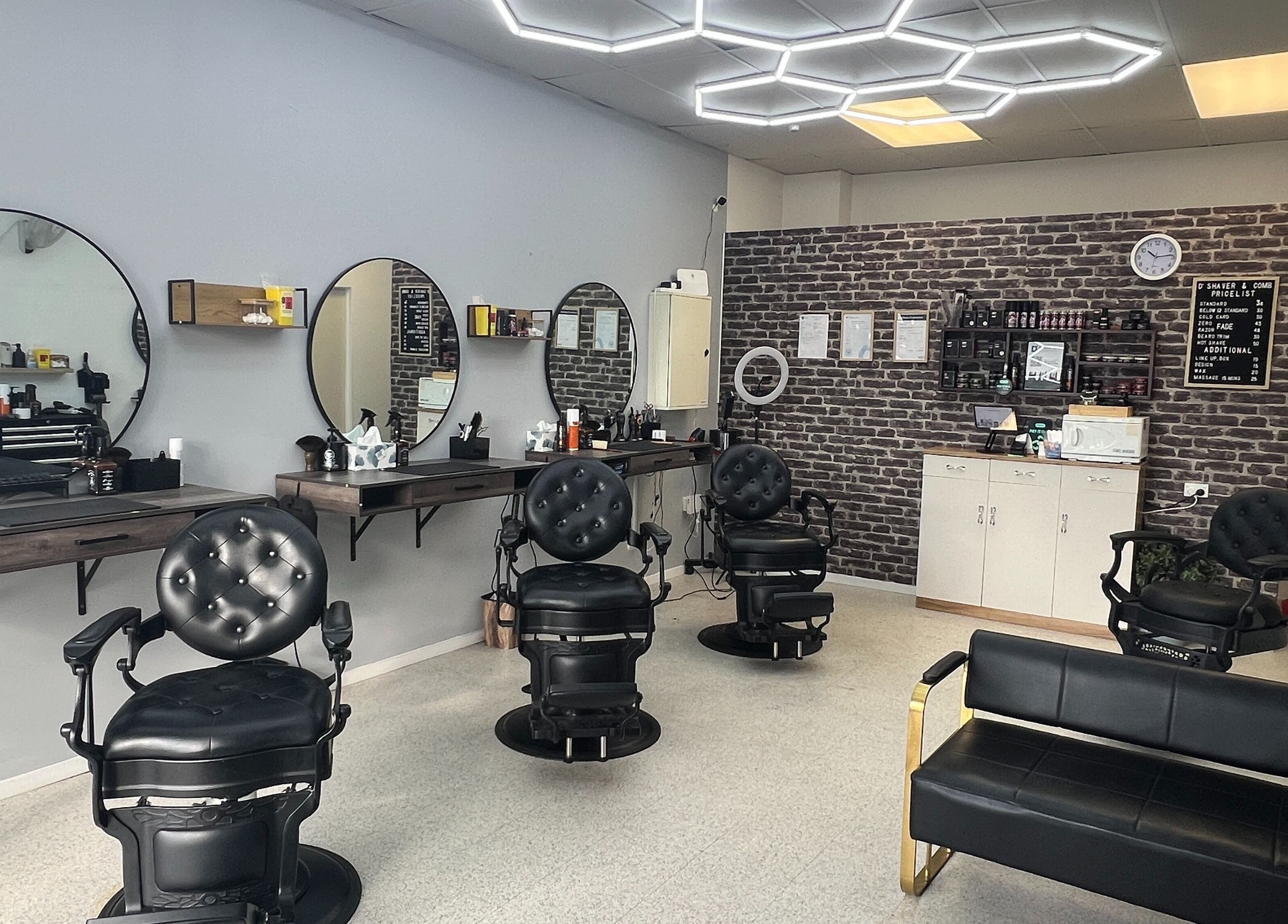 Modern interior of D' Shaver And Comb Barbershop, Auckland, NZ, featuring sleek black chairs and mirrors.