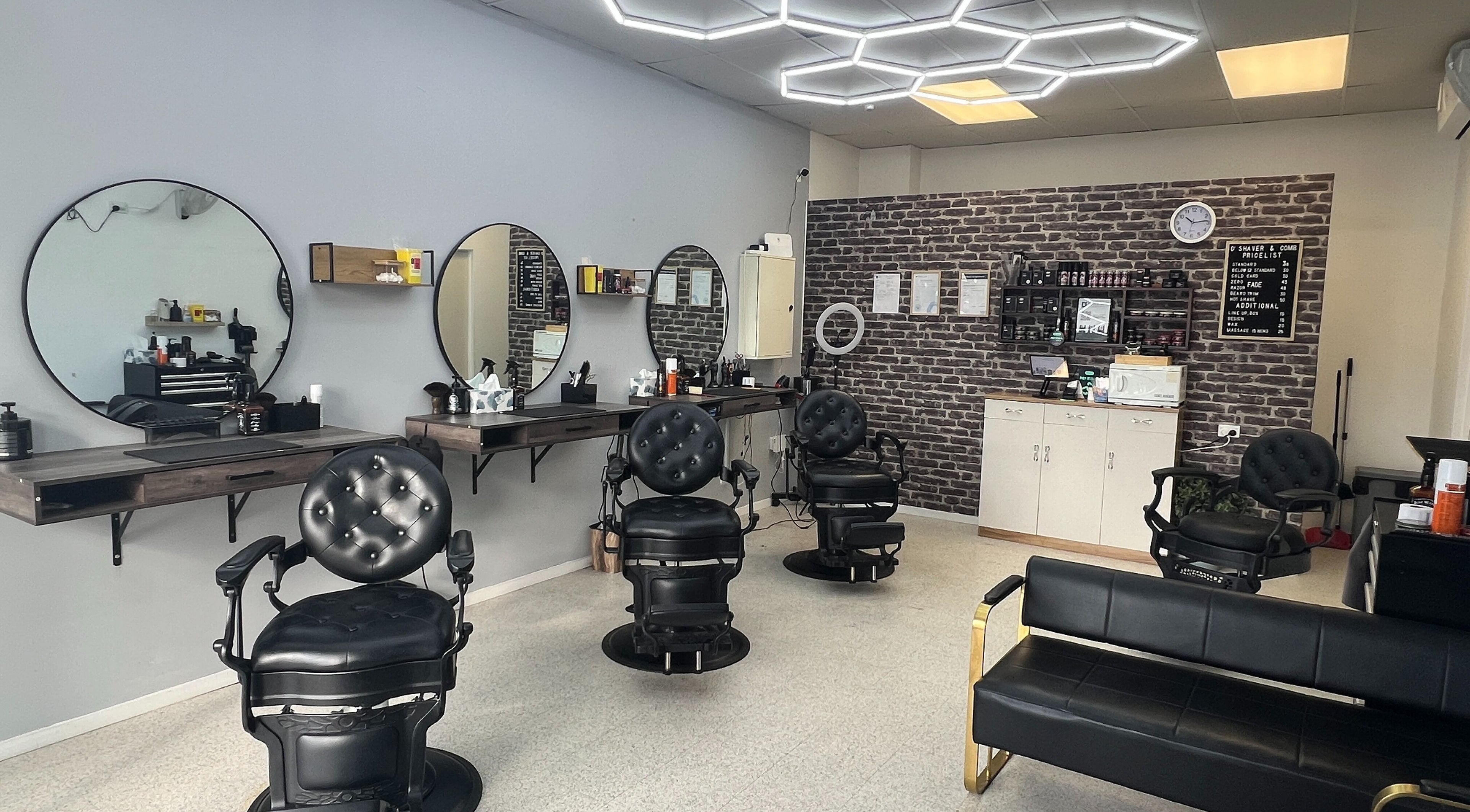 Modern interior of D' Shaver And Comb Barbershop, Auckland, NZ, featuring sleek black chairs and mirrors.