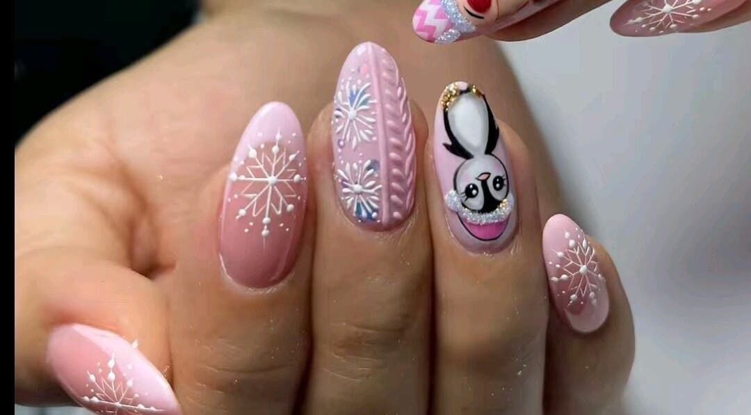 Elegant winter-themed nail art at Jenny Agudelo in CO featuring snowflakes and penguin design.