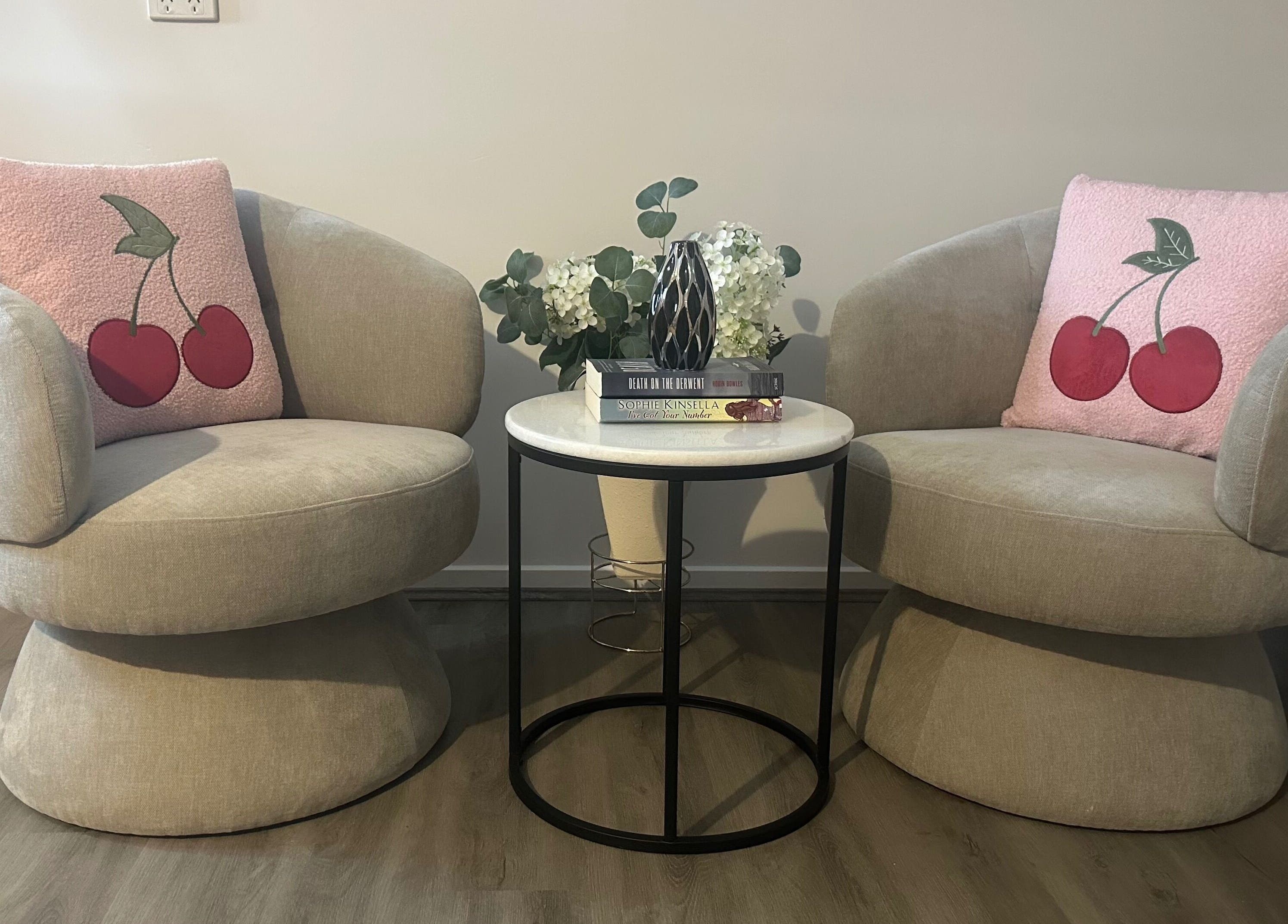Two chic beige chairs with cherry pillows at Glow By Candice K, Melbourne, Victoria, AU.