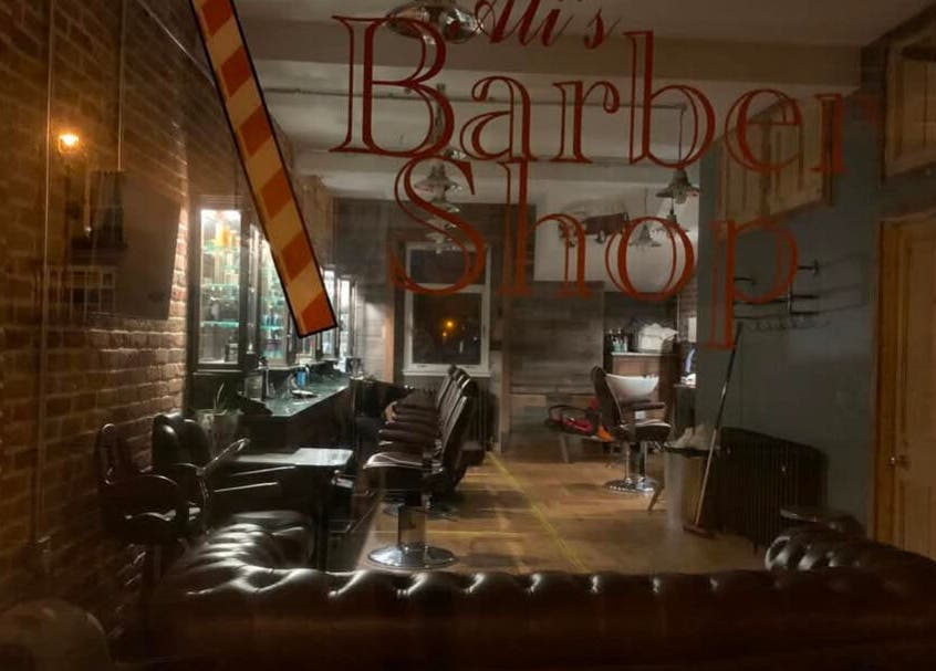 Interior of JW BARBERING in Pembroke, Wales, GB showcasing vintage barber chairs and rustic brick walls.