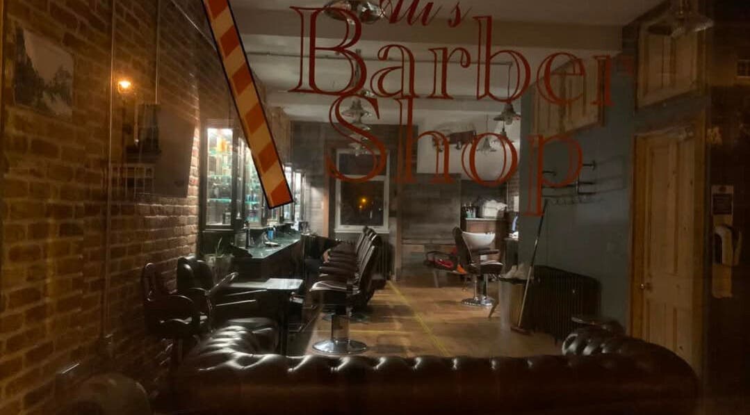 Interior of JW BARBERING in Pembroke, Wales, GB showcasing vintage barber chairs and rustic brick walls.