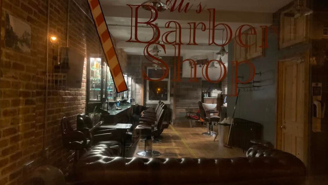 Interior of JW BARBERING in Pembroke, Wales, GB showcasing classic leather chairs and rustic decor.
