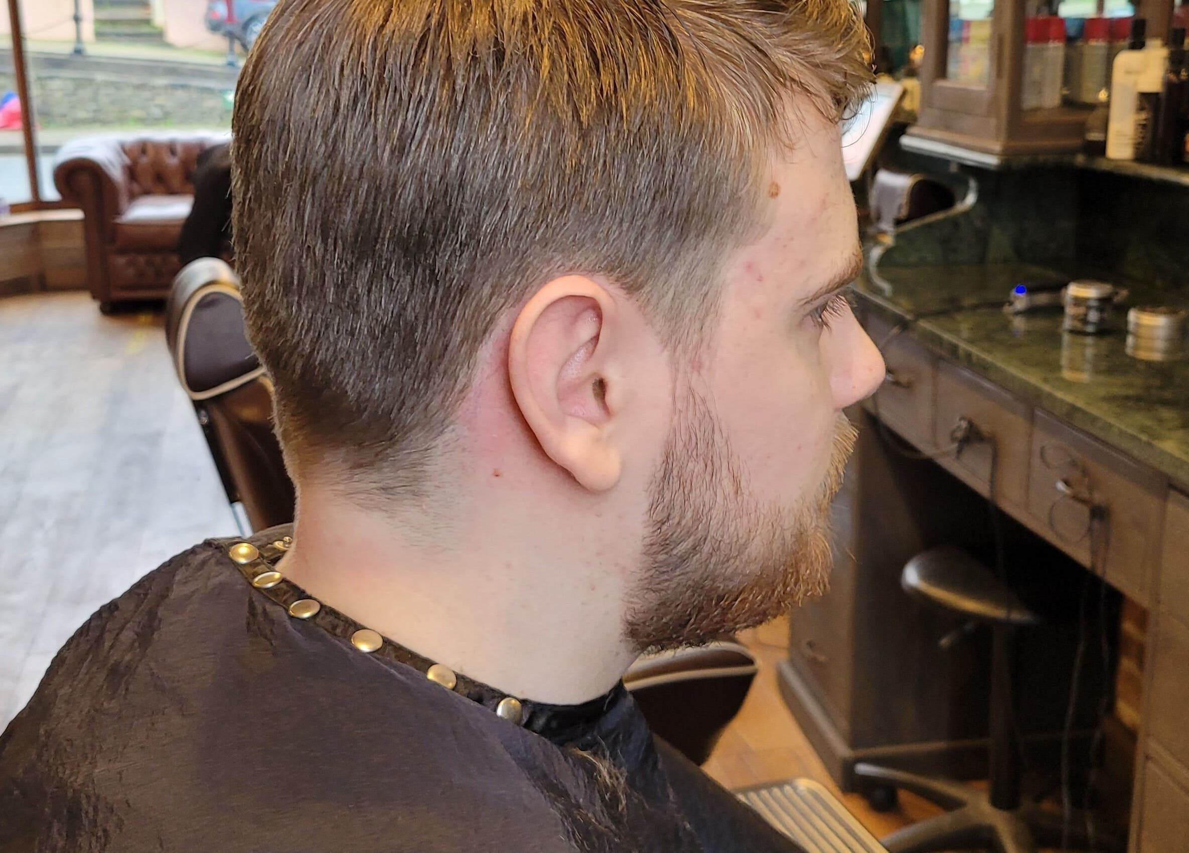 Side view of a man's haircut at JW BARBERING, Pembroke, Wales, GB, showcasing a stylish grooming environment.