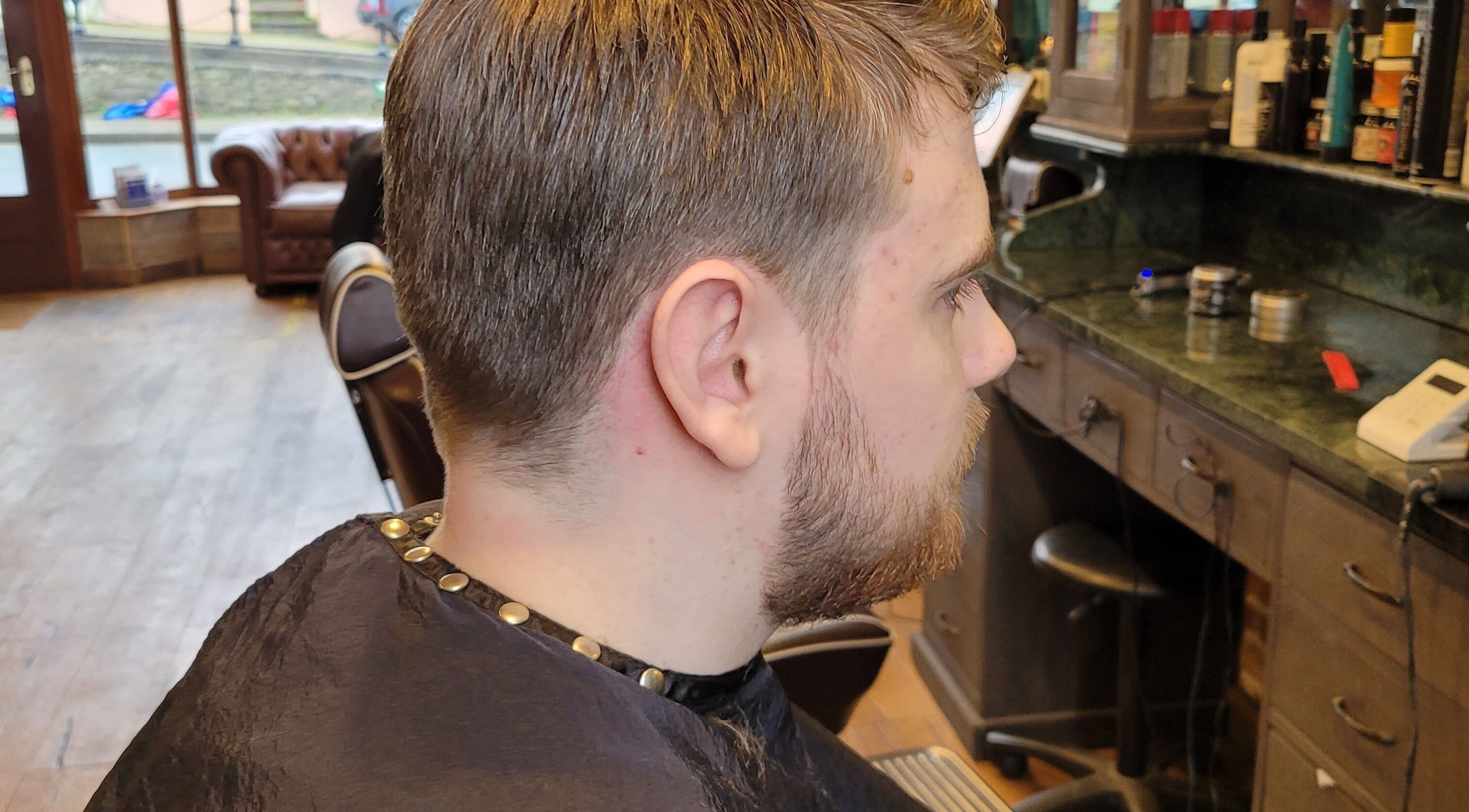 Side view of a man's haircut at JW BARBERING, Pembroke, Wales, GB, showcasing a stylish grooming environment.